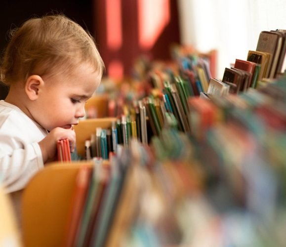 toddler-looking-through-books-min